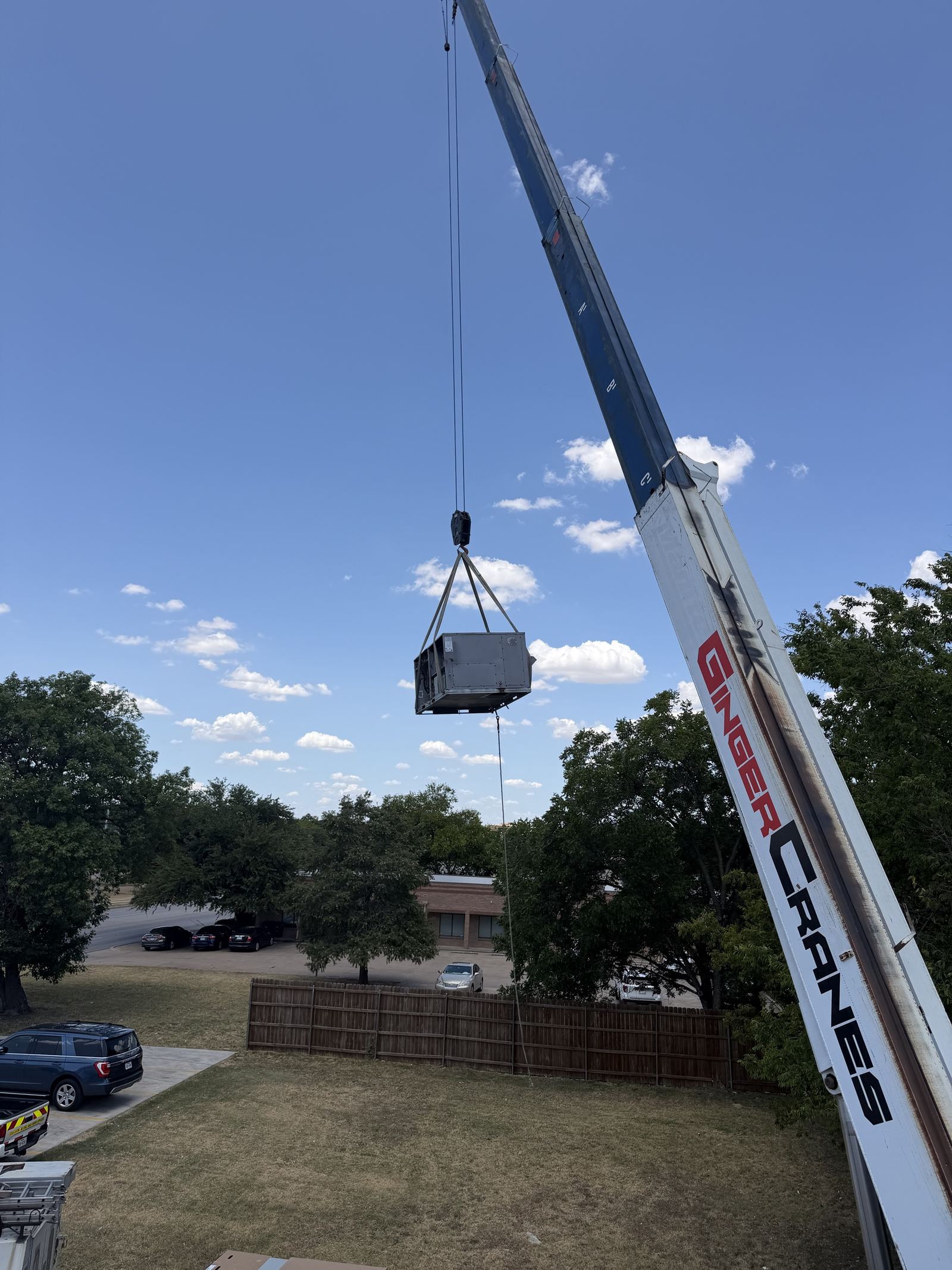 Crane lifting a commercial rooftop HVAC package unit into place